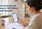 A woman reviews a SEPA direct debit mandate form and her banking app at a kitchen table.