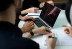 Finance team reviewing multi-entity financial consolidation reports together around a laptop