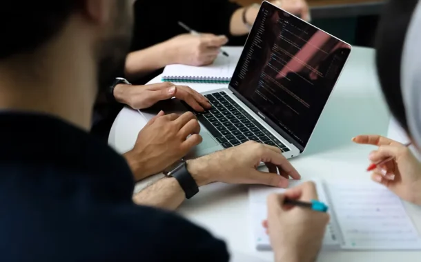 Finance team reviewing multi-entity financial consolidation reports together around a laptop