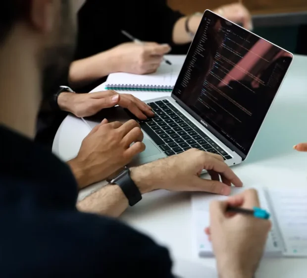 Finance team reviewing multi-entity financial consolidation reports together around a laptop