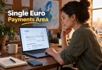 A studio owner reviews an invoice with SEPA transfer details and a euro IBAN on a laptop.